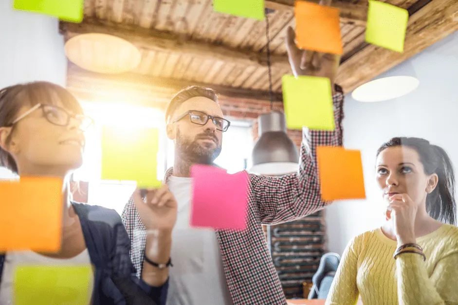 Team reviewing ideas on sticky notes. Revisiting your strategy is a marketing essential to recession-proof your business.
