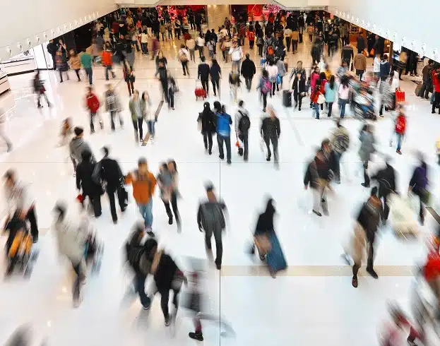 Crowd of shoppers walking through a busy mall.