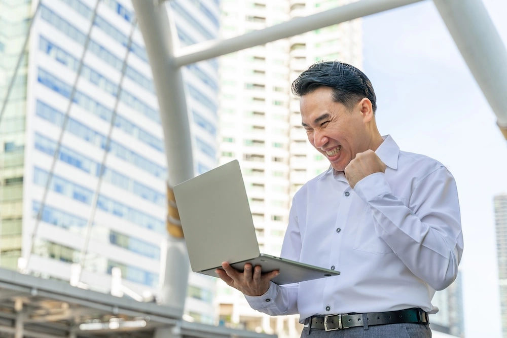 psg-grant-approval Businessman looking happy looking at a laptop